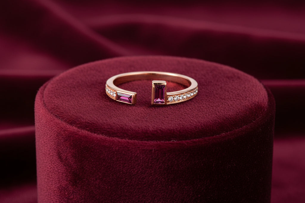 A gold band ring with one ruby and one diamond gemstone on top, set in a claw-like setting.